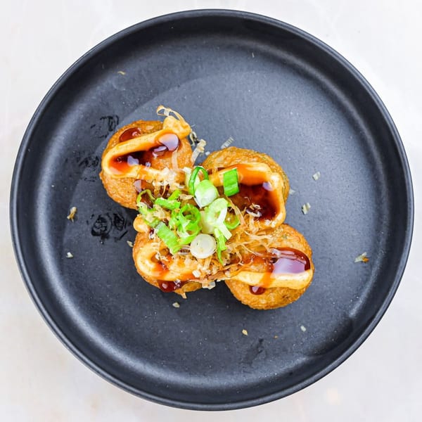 Sweetfish Poké Bowls & Sushi's takoyaki, topped with sauce, mayonnaise, green onions, and bonito flakes.