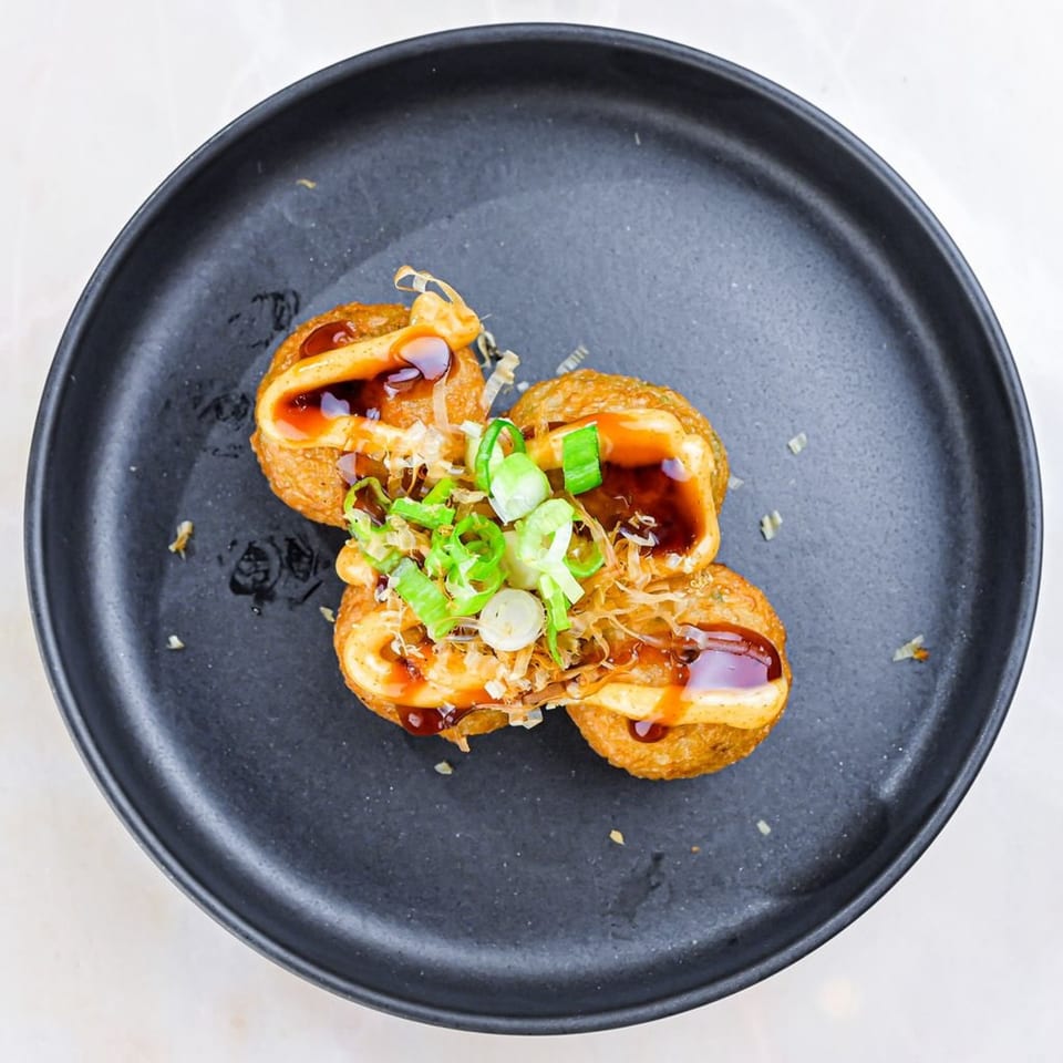Sweetfish Poké Bowls & Sushi's takoyaki, topped with sauce, mayonnaise, green onions, and bonito flakes.