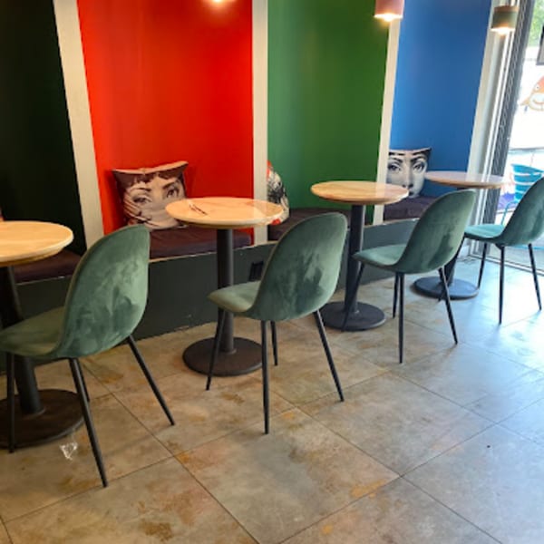 Sweetfish Poké Bowls & Sushi interior with colorful walls, green chairs, and small round tables.