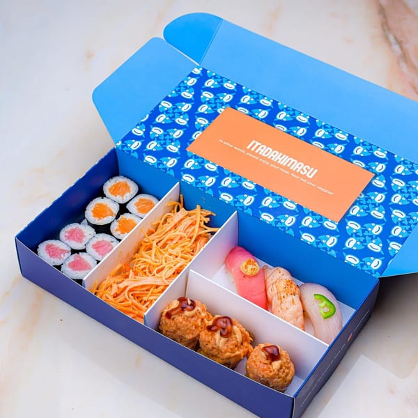 An open Sweetfish Poké Bowls & Sushi box filled with various sushi rolls, nigiri, and crab salad.